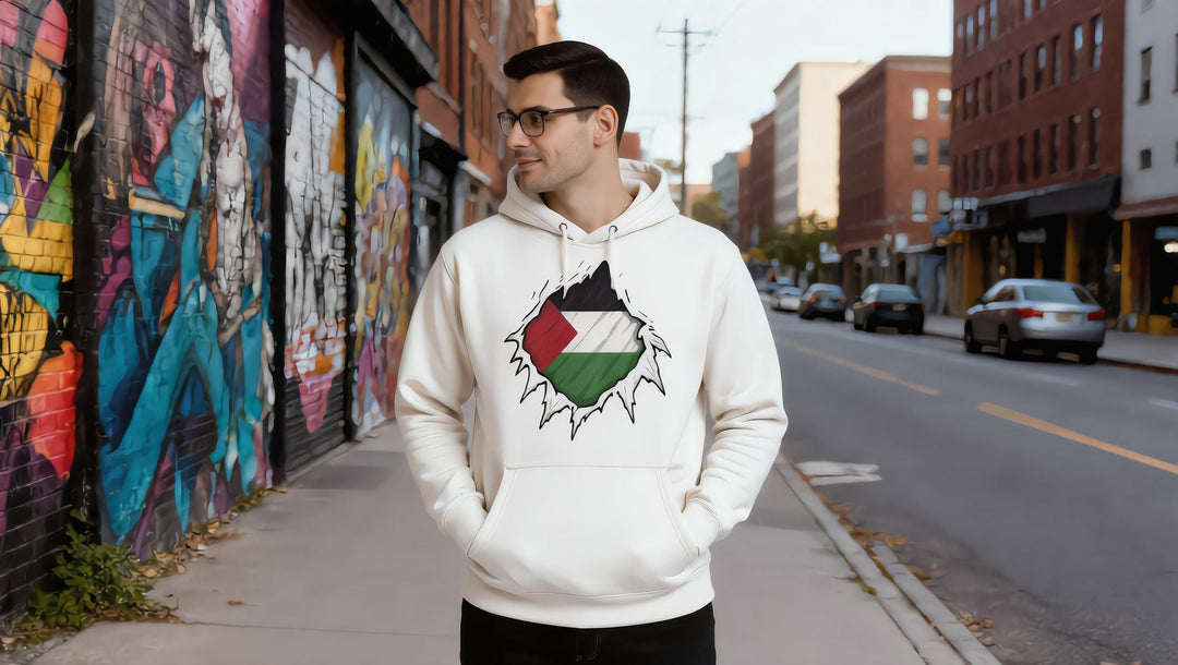 Man in a white Palestine Hero hoodie on a Williamsburg street with murals